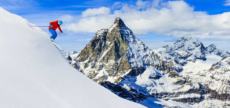 Skier skiing downhill in high mountains, Zermatt Alps region Switzerland